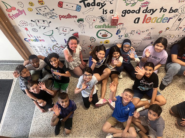 A group of students in front of a mural they created for the 2024 Summer Discovery Program at Lindbergh.